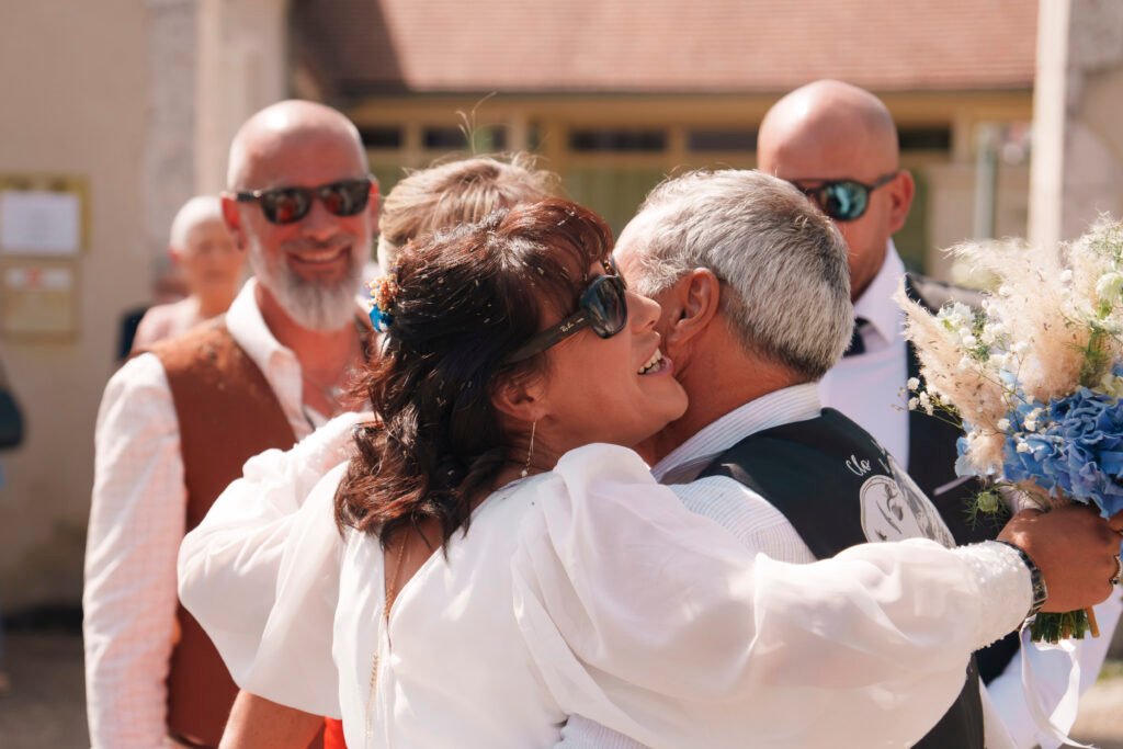 La mariée fait un calin à un ami à la sortie de mairie | Photographe de mariage à Bourges