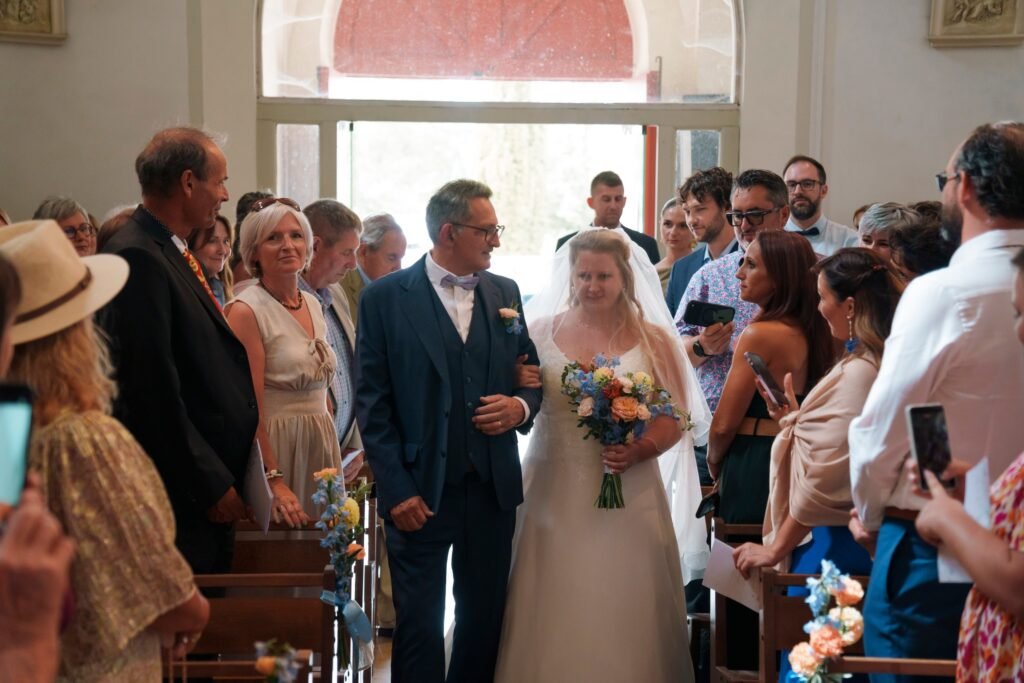 La mariée entre dans l'église de Fussy au bras de son père