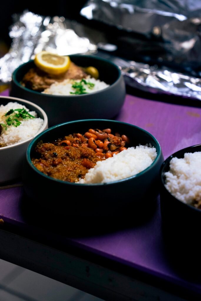 Bols de riz, haricots et poisson au citron alignés sur le plan de travail d'un traiteur