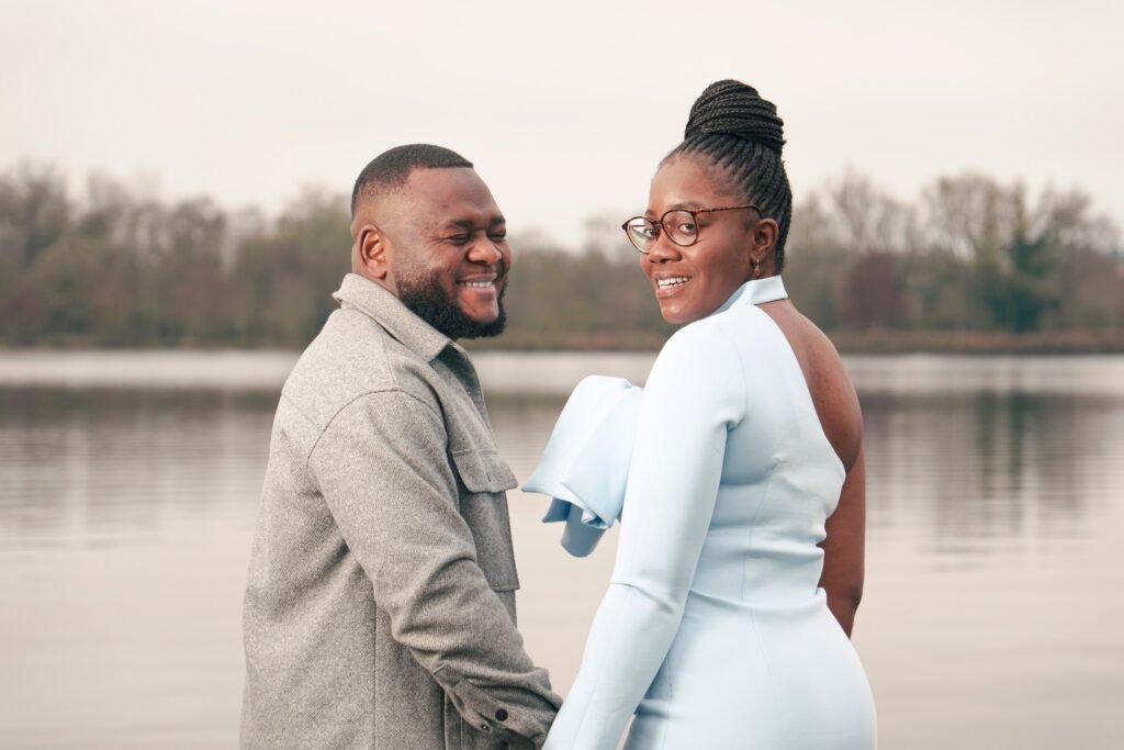 Fiancés de dos qui se retournent en riant, main dans la main face à l'étang, séance engagement dans le Cher