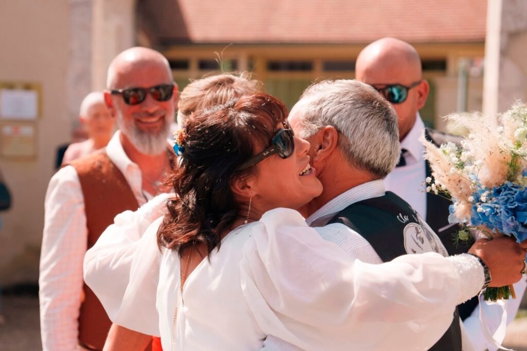 La mariée fait un calin à un ami à la sortie de mairie | Photographe de mariage à Bourges
